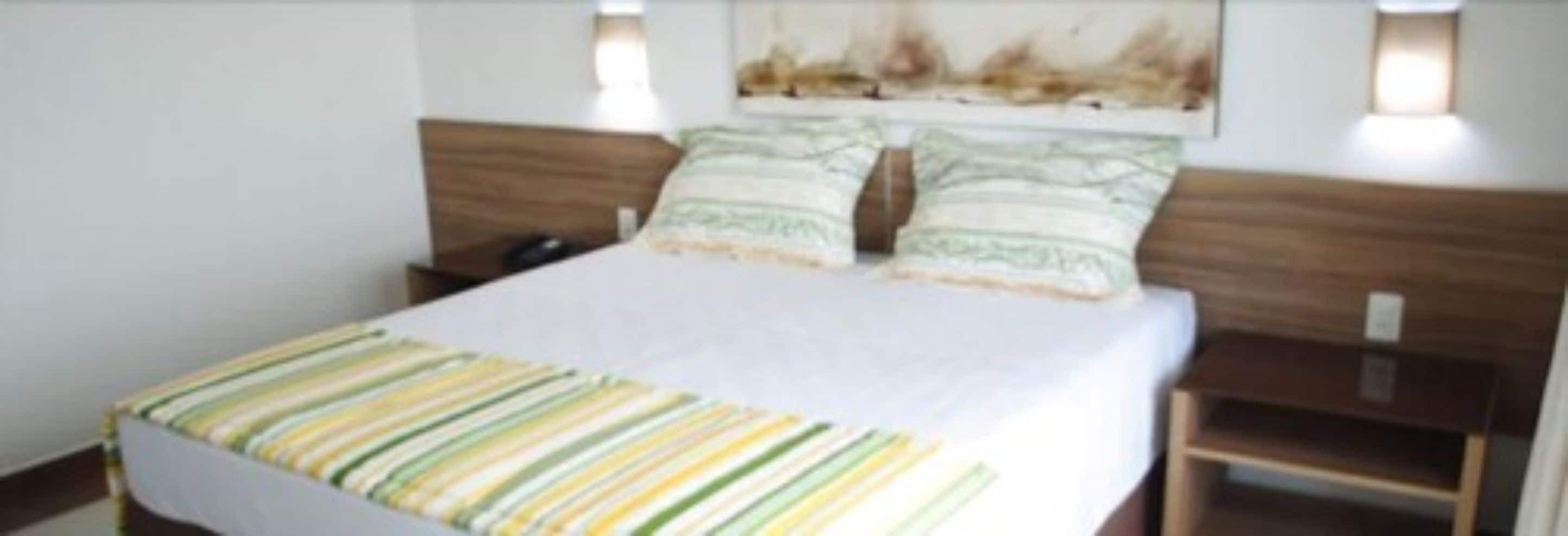 A neatly made bed with striped bedding, a wooden headboard, and two bedside lamps.