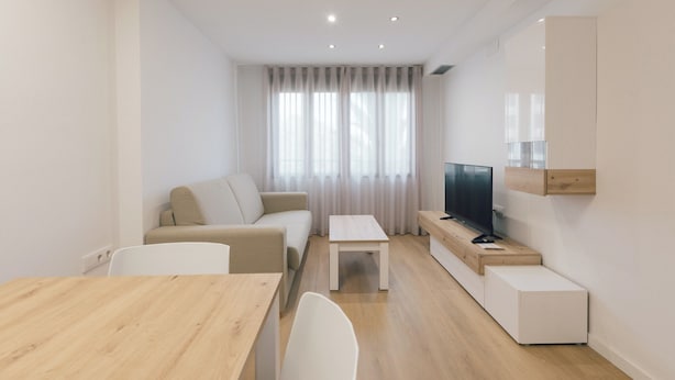 Una sala de estar moderna y minimalista con un sofá, una mesa de centro, un televisor y un aparador de madera.