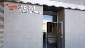 Entrada de un edificio moderno con un cartel que dice 'Pio XII Apartments'.