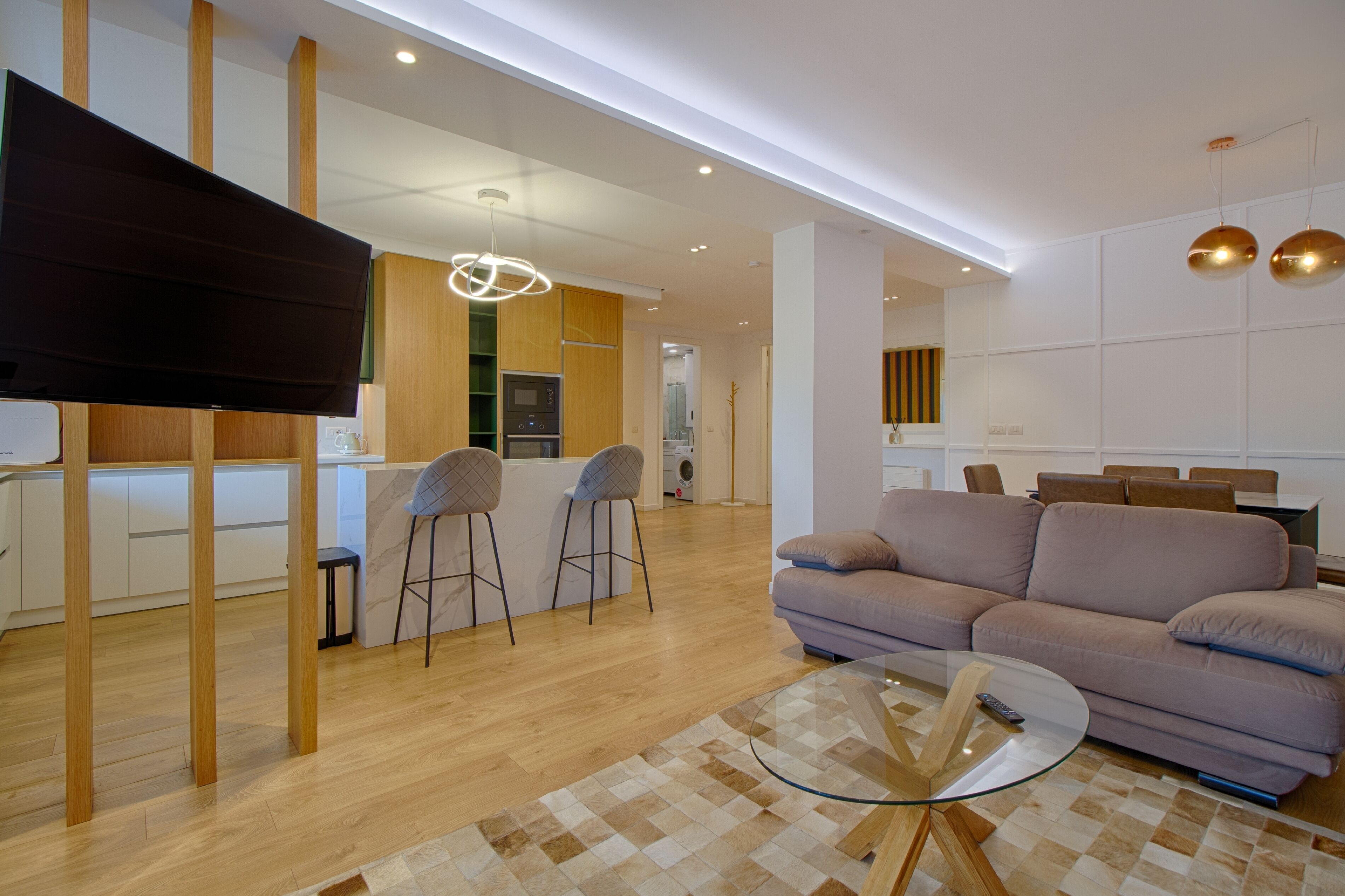 Un salon moderne avec un canapé, une table basse en verre et un téléviseur posé sur un meuble.