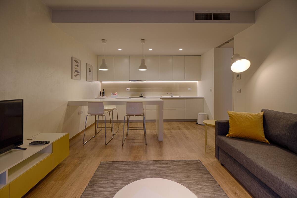 Una sala de estar moderna con un sofá, un televisor y un comedor con sillas y una mesa.