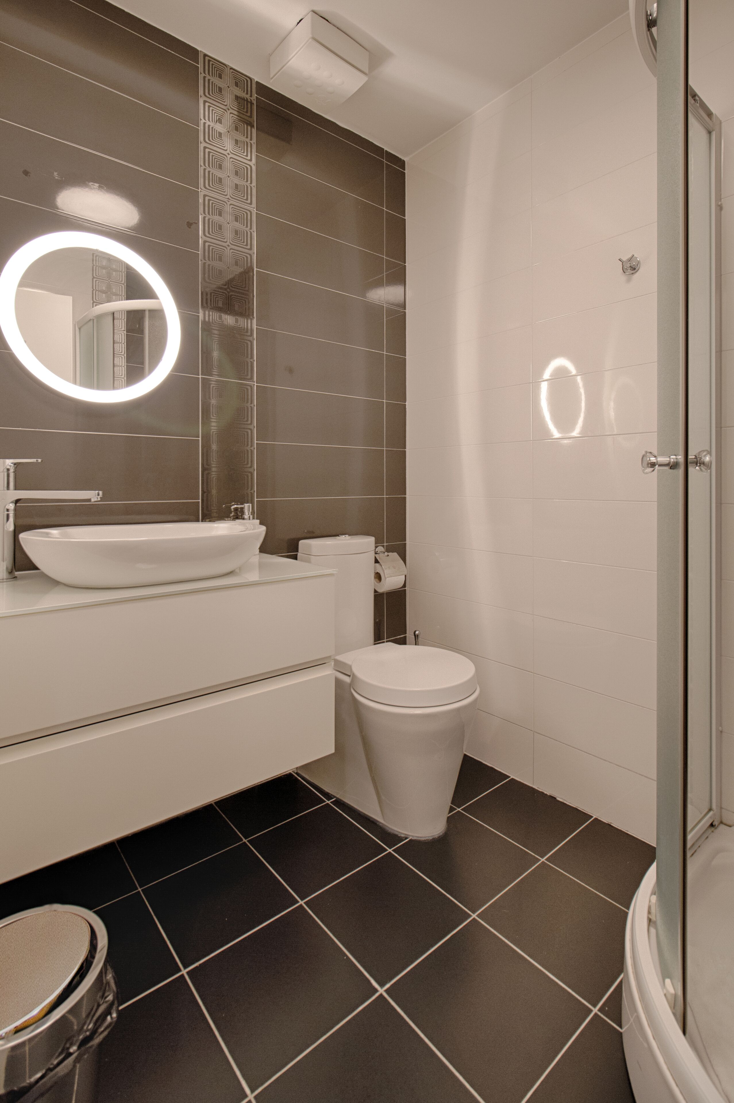 Een moderne badkamer met een wit wastafel, toilet en douche.