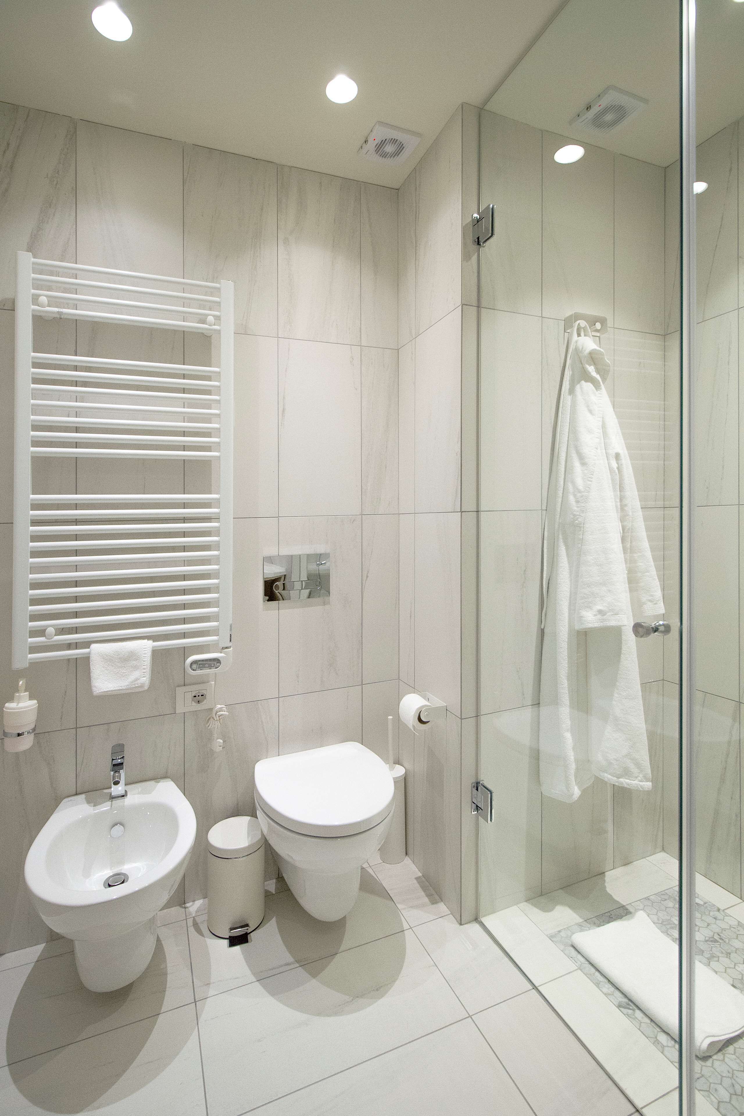 A modern bathroom with a bidet, toilet, and glass shower enclosure.