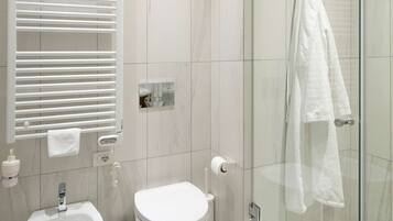 A modern bathroom with a bidet, toilet, and glass shower enclosure.