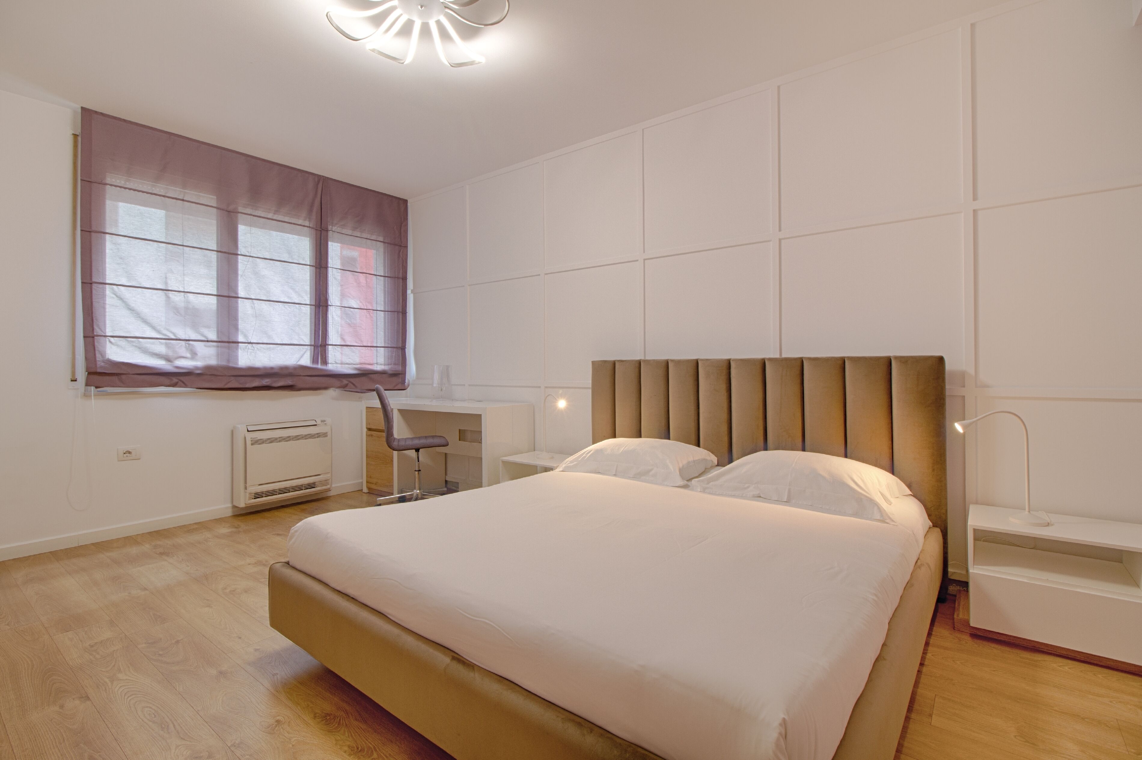 Un dormitorio con una cama grande, un escritorio, una silla y una ventana con persianas.