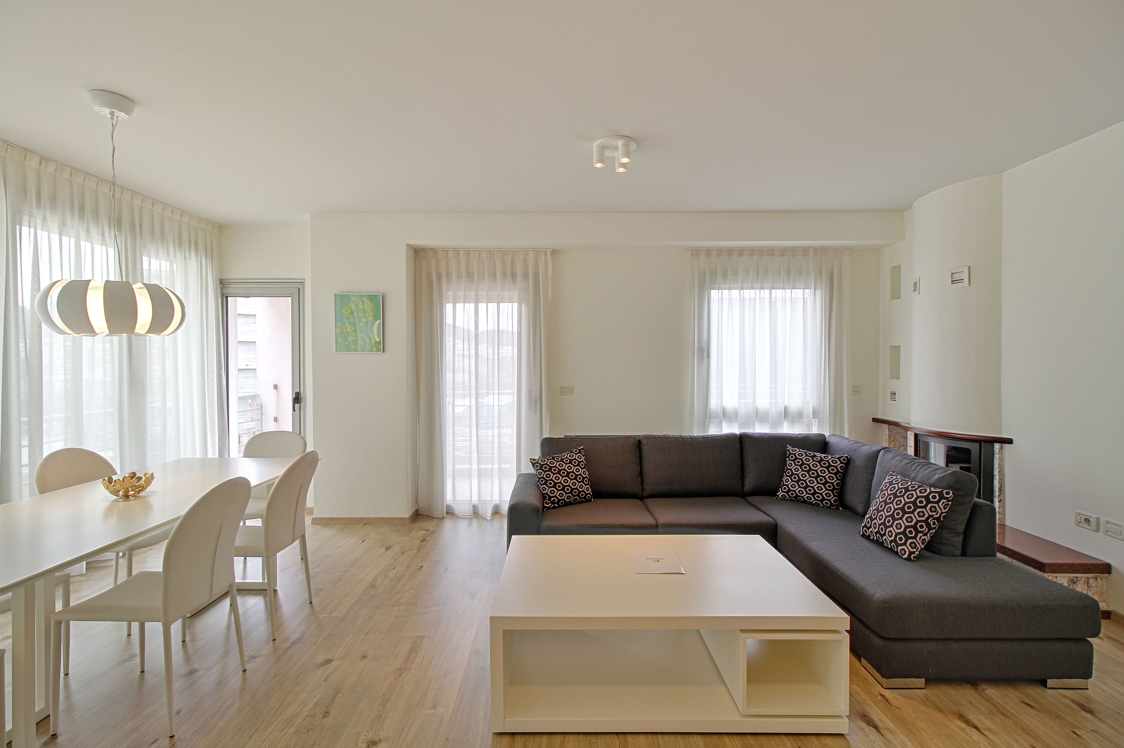 Una sala de estar moderna con un sofá modular, una mesa de comedor con sillas y una mesa de centro.