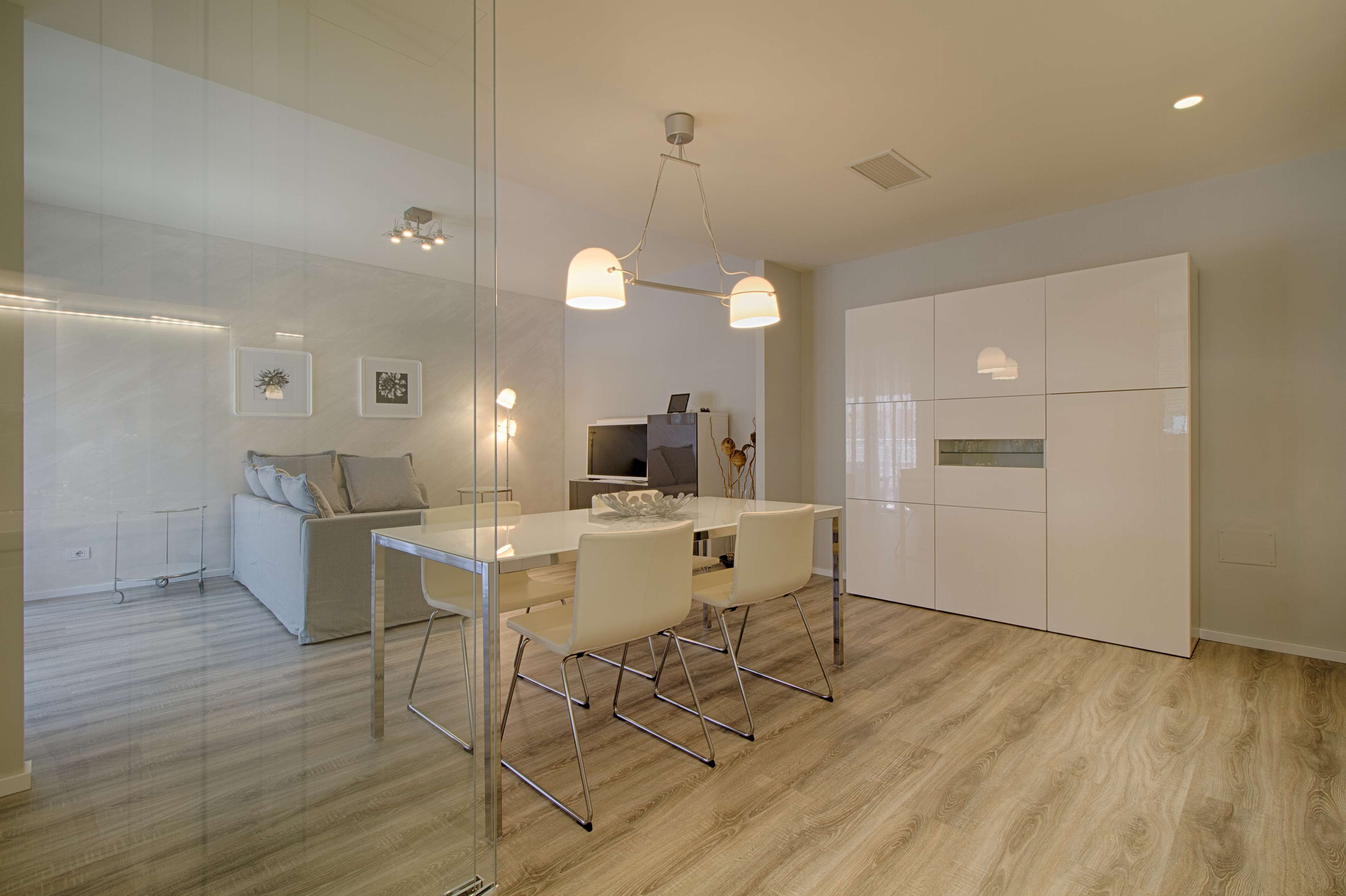 Une cuisine moderne dotée d’un îlot central, de meubles blancs et d’une cloison en verre.