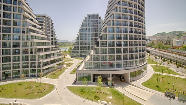 A modern urban complex with multi-story buildings, a central courtyard, and a curved structure.