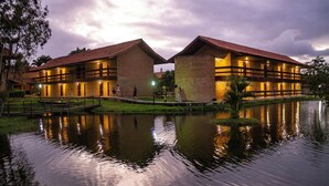 Un edificio con un cuerpo de agua reflectante en primer plano, que incluye un puente y una pequeña isla.