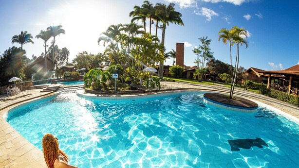 Una piscina con agua cristalina, rodeada de palmeras y un edificio de ladrillo.