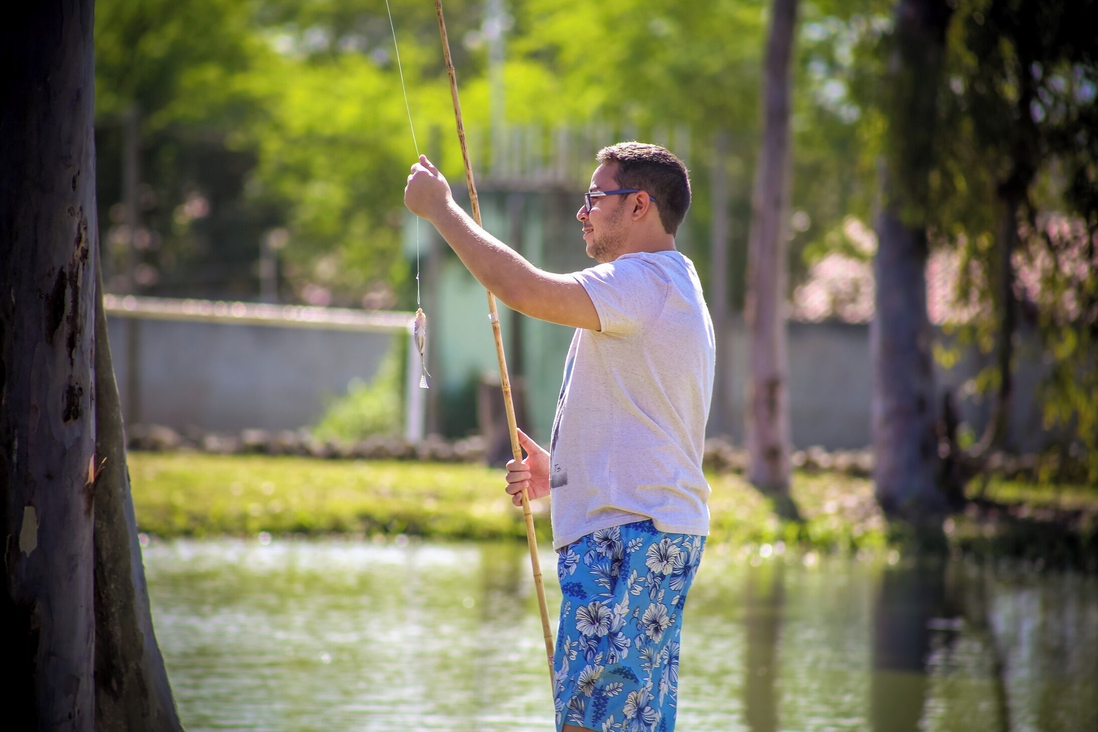 A person standing by a body of water, holding a fishing rod.