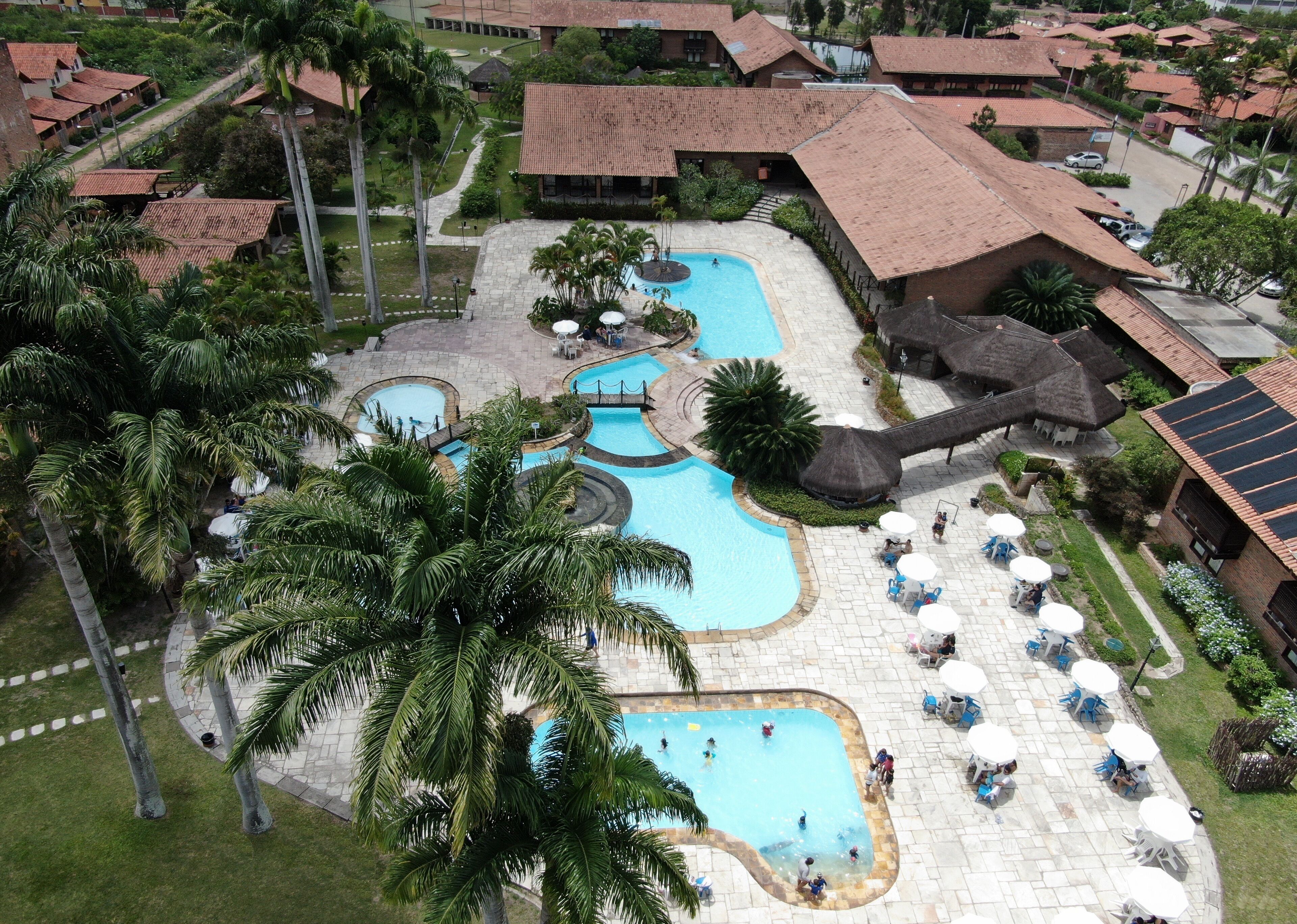 A resort with multiple swimming pools, palm trees, and outdoor seating areas.