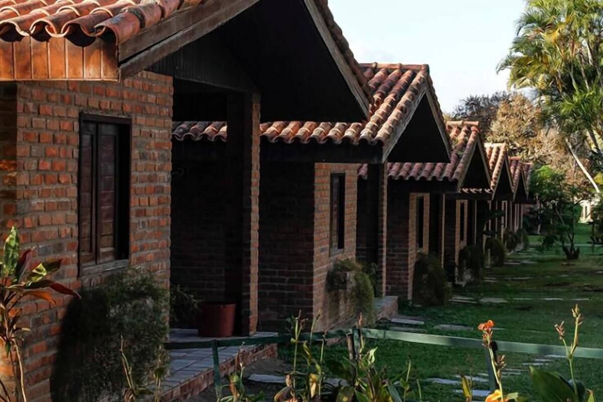 A row of brick buildings with tiled roofs, a paved pathway, and some greenery.
