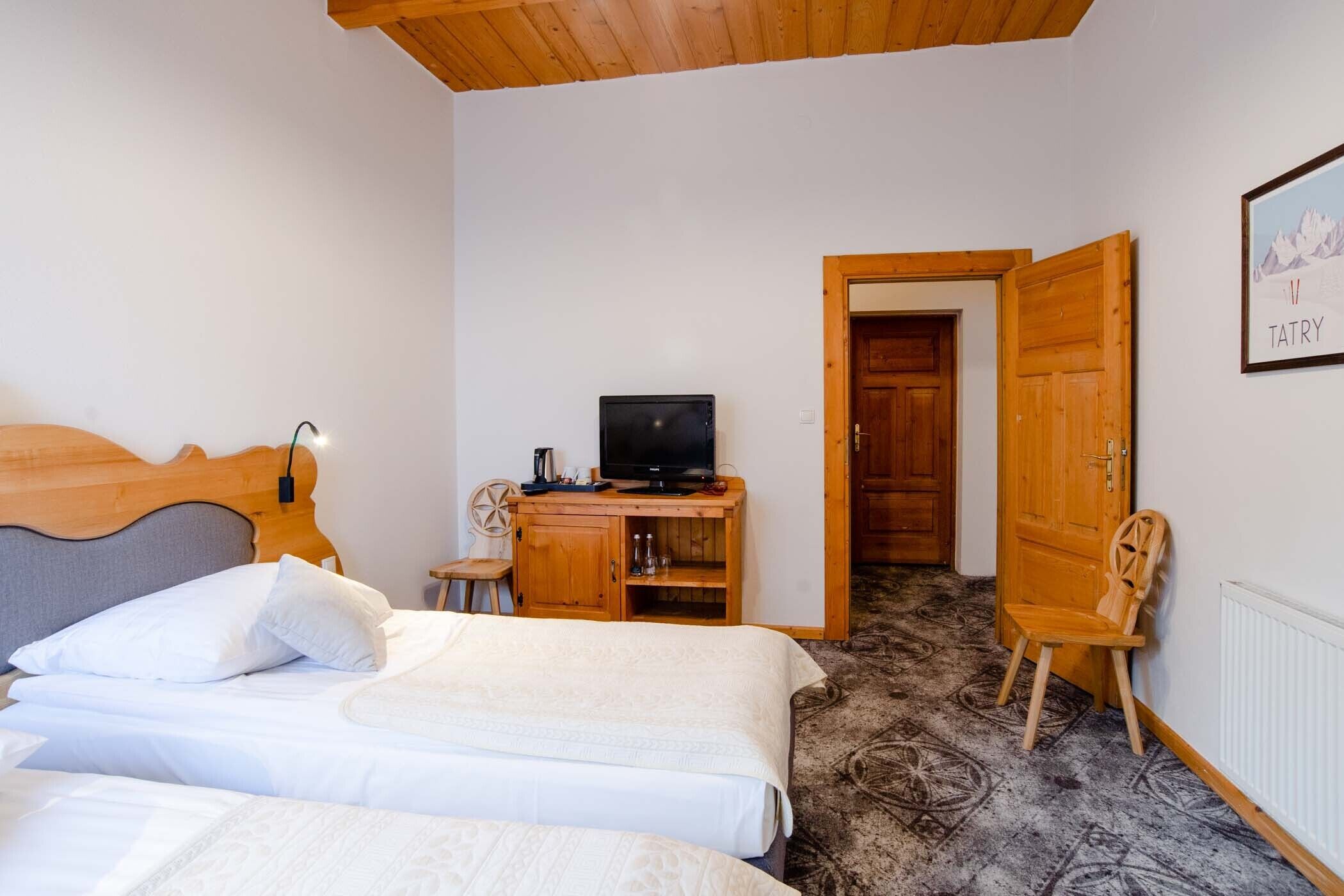 Un dormitorio con dos camas, un escritorio de madera con un televisor y una puerta que da a otra habitación.