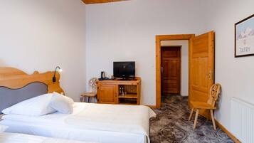 Un dormitorio con dos camas, un escritorio de madera con un televisor y una puerta que da a otra habitación.