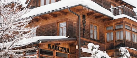 A wooden building with a sign reading "Karczma" in front.