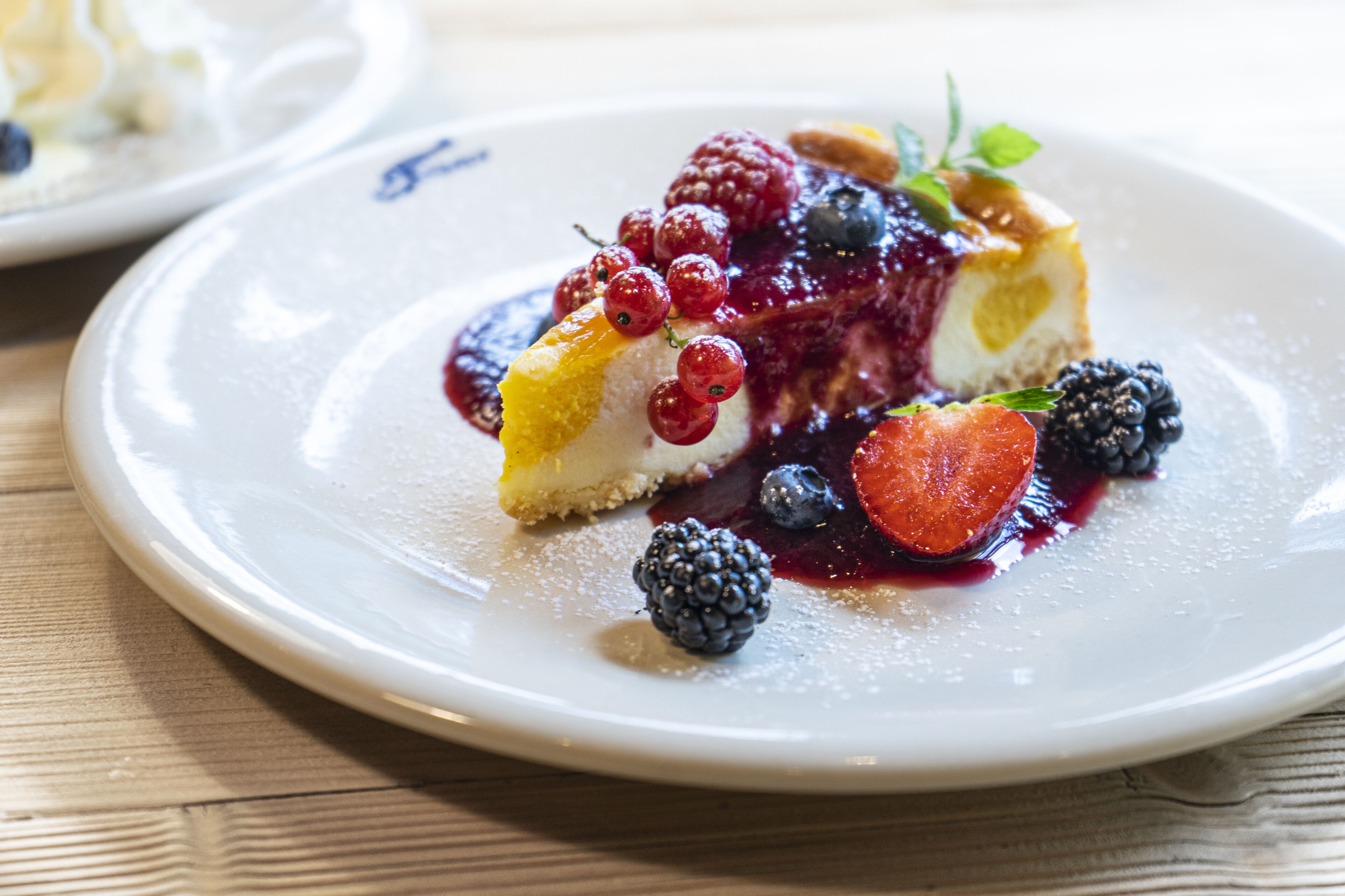 A dessert plate with a slice of cheesecake topped with berries and a berry sauce.