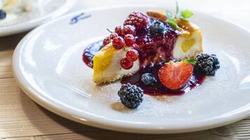 A dessert plate with a slice of cheesecake topped with berries and a berry sauce.