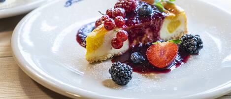 A dessert plate with a slice of cheesecake topped with berries and a berry sauce.