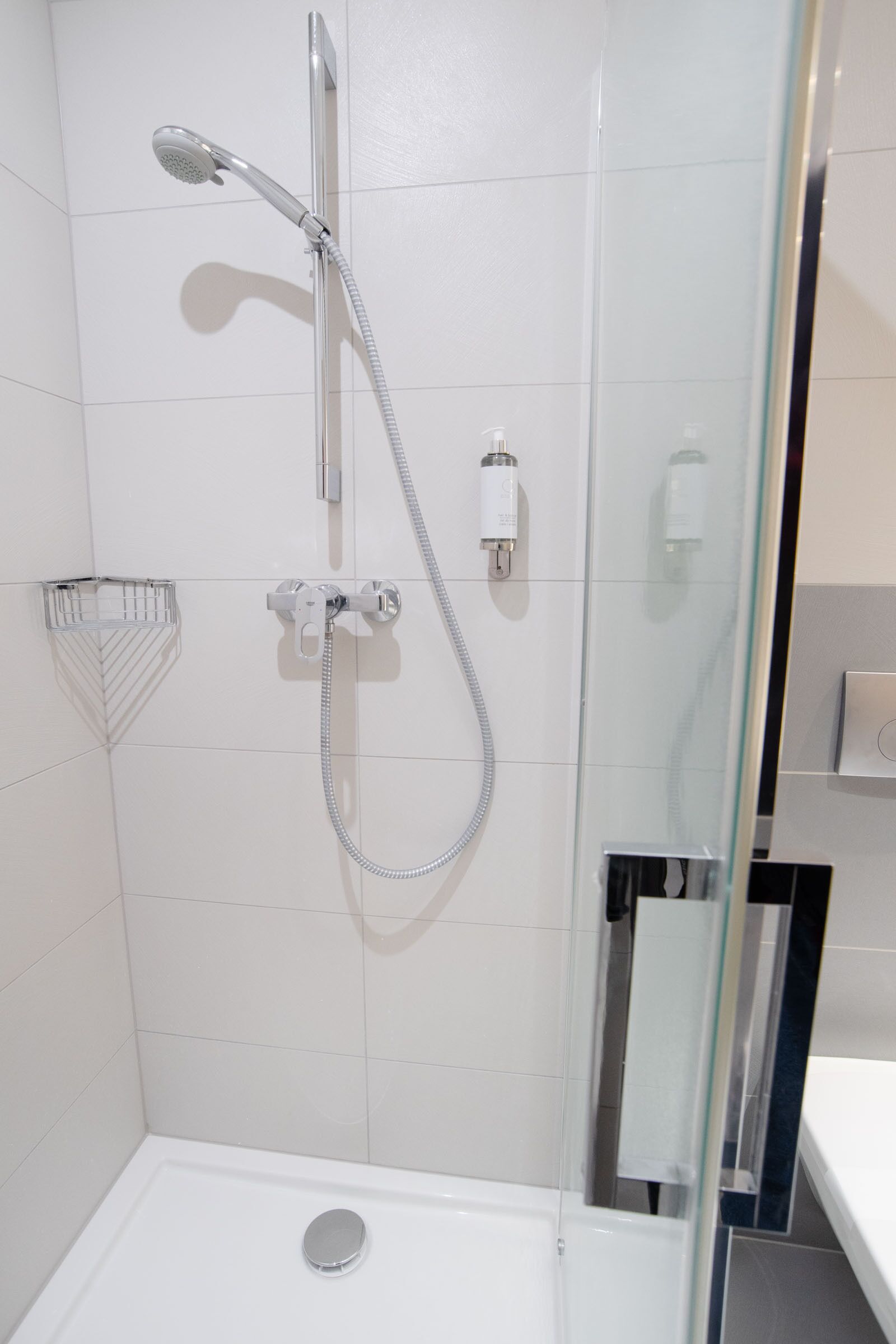 Une douche moderne dotée d’un pommeau de douche à main et d’un robinet mural.