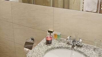 A bathroom with a glass-enclosed shower, a granite sink, and a towel rack.
