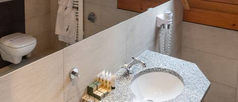 A modern bathroom with a skylight, a freestanding bathtub, and a vanity with toiletries.