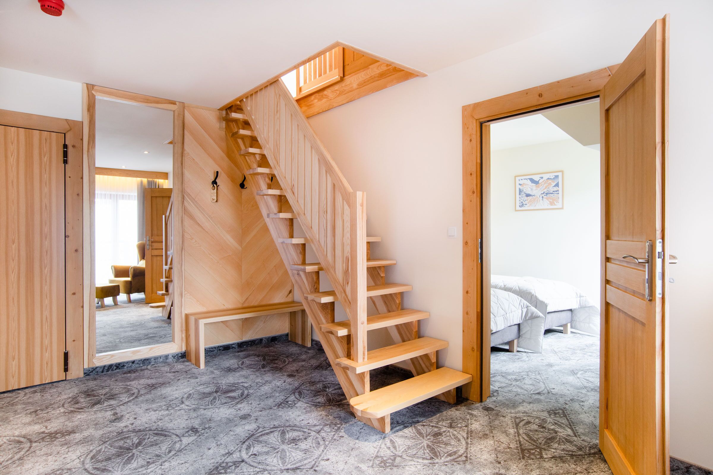 A wooden staircase leading to a bedroom with a bed and a nightstand.