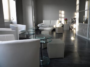 A modern living room with white furniture, glass tables, and a minimalist design. - Hôtel Alerion (Metz)