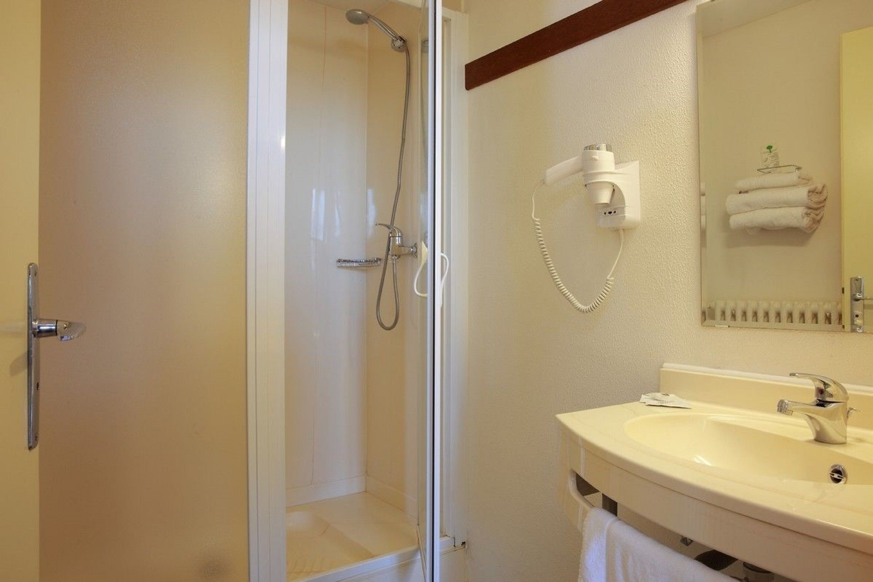 A bathroom with a glass-enclosed shower, a sink with a mirror, and a towel rack with towels.
