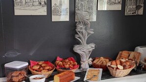A breakfast buffet with various pastries, bread, and a cake on a marble countertop. - Hôtel Alerion (Metz)