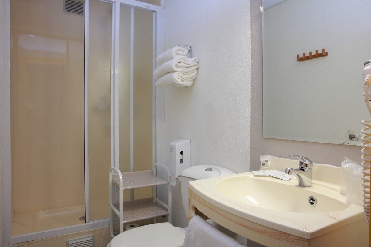 Un baño con ducha, inodoro, lavamanos y barra para toallas.