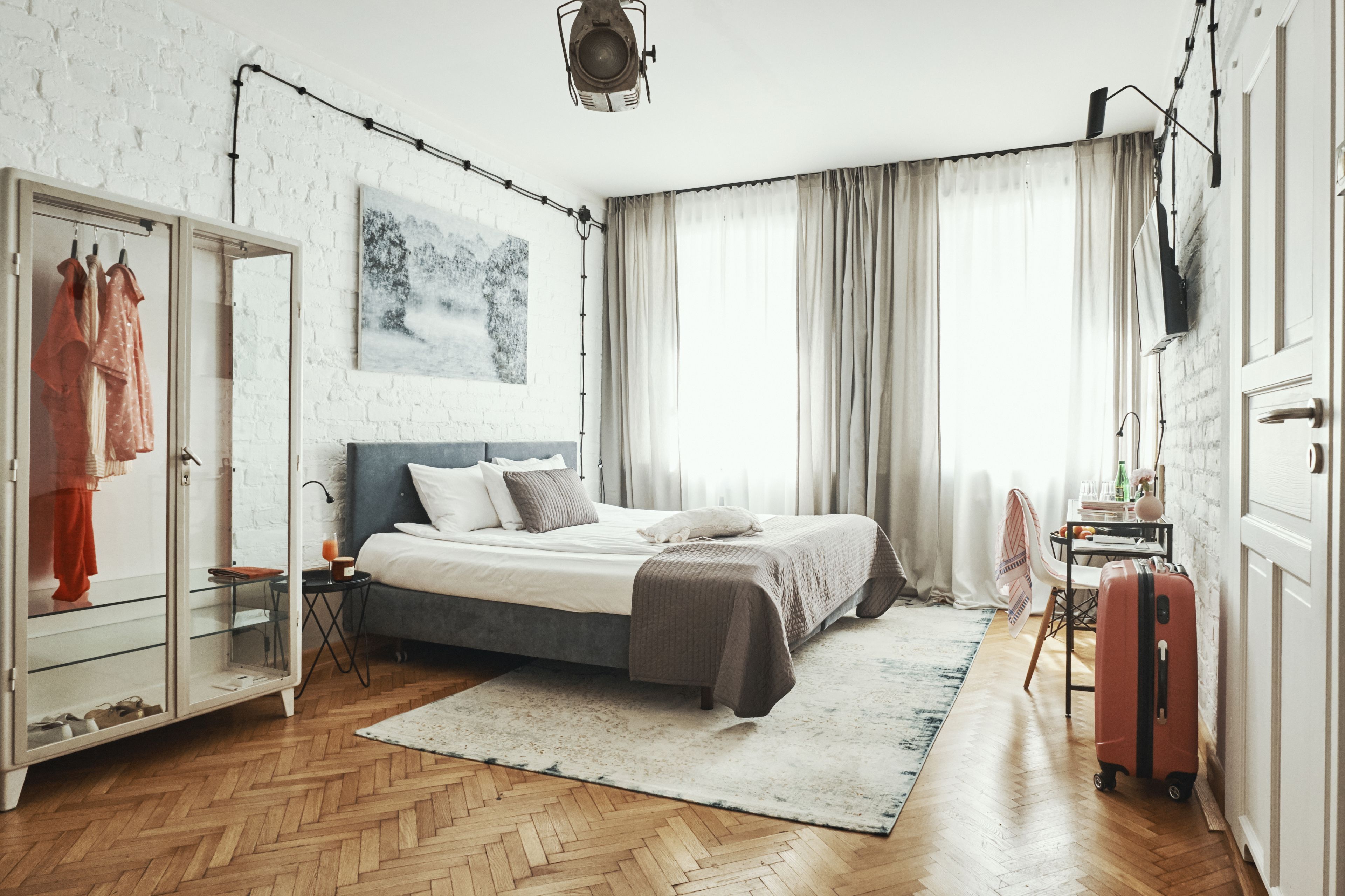 A bedroom with a bed, a wardrobe, a desk, and a suitcase.
