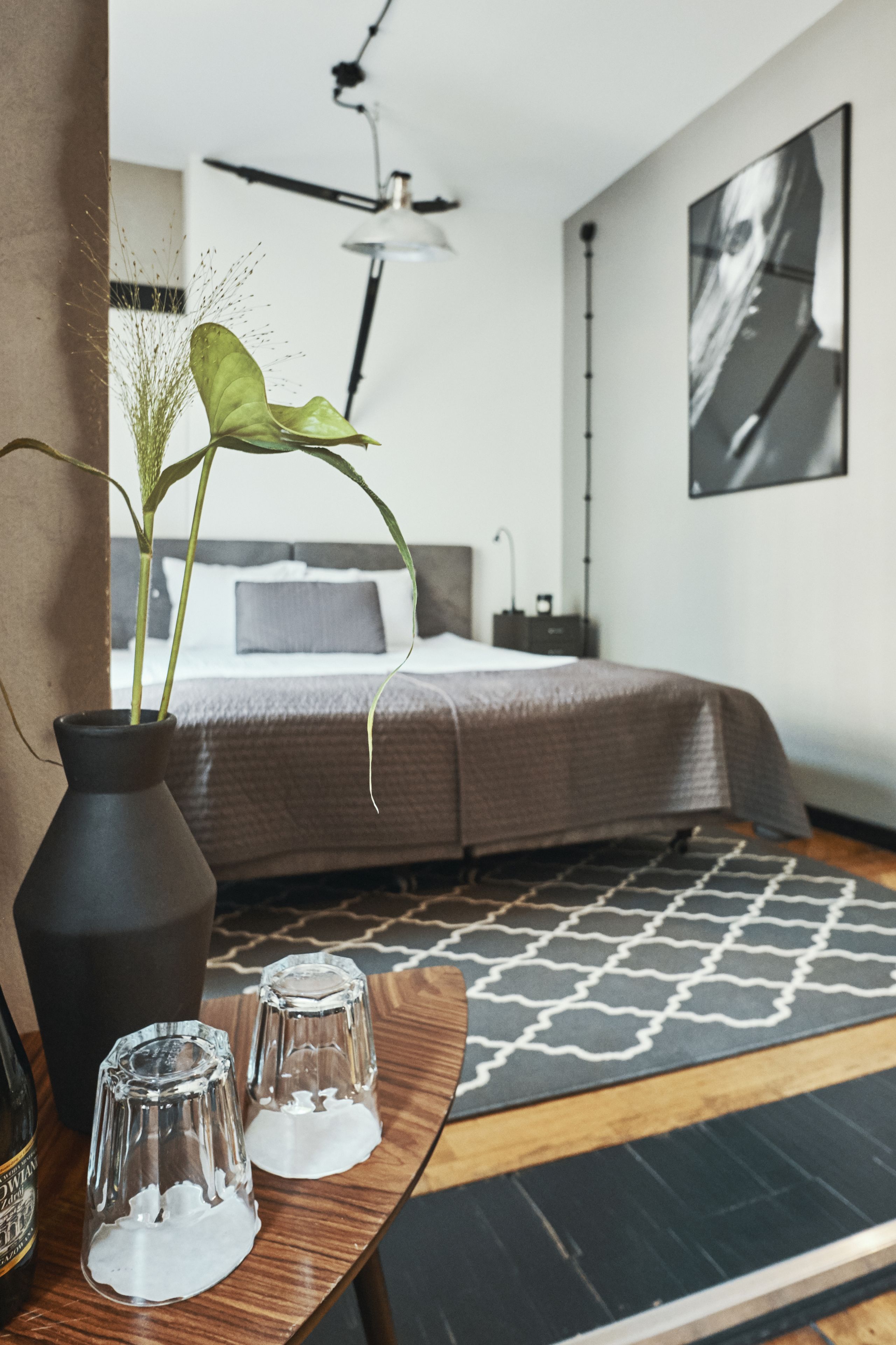 A modern bedroom with a bed, bedside table, and a large window.