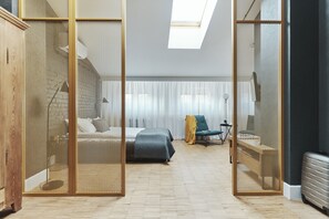 A modern bedroom with a bed, a desk, and a chair. There is a window with sheer curtains and a skylight. - Arthotel Stalowa 52 (Warsaw)