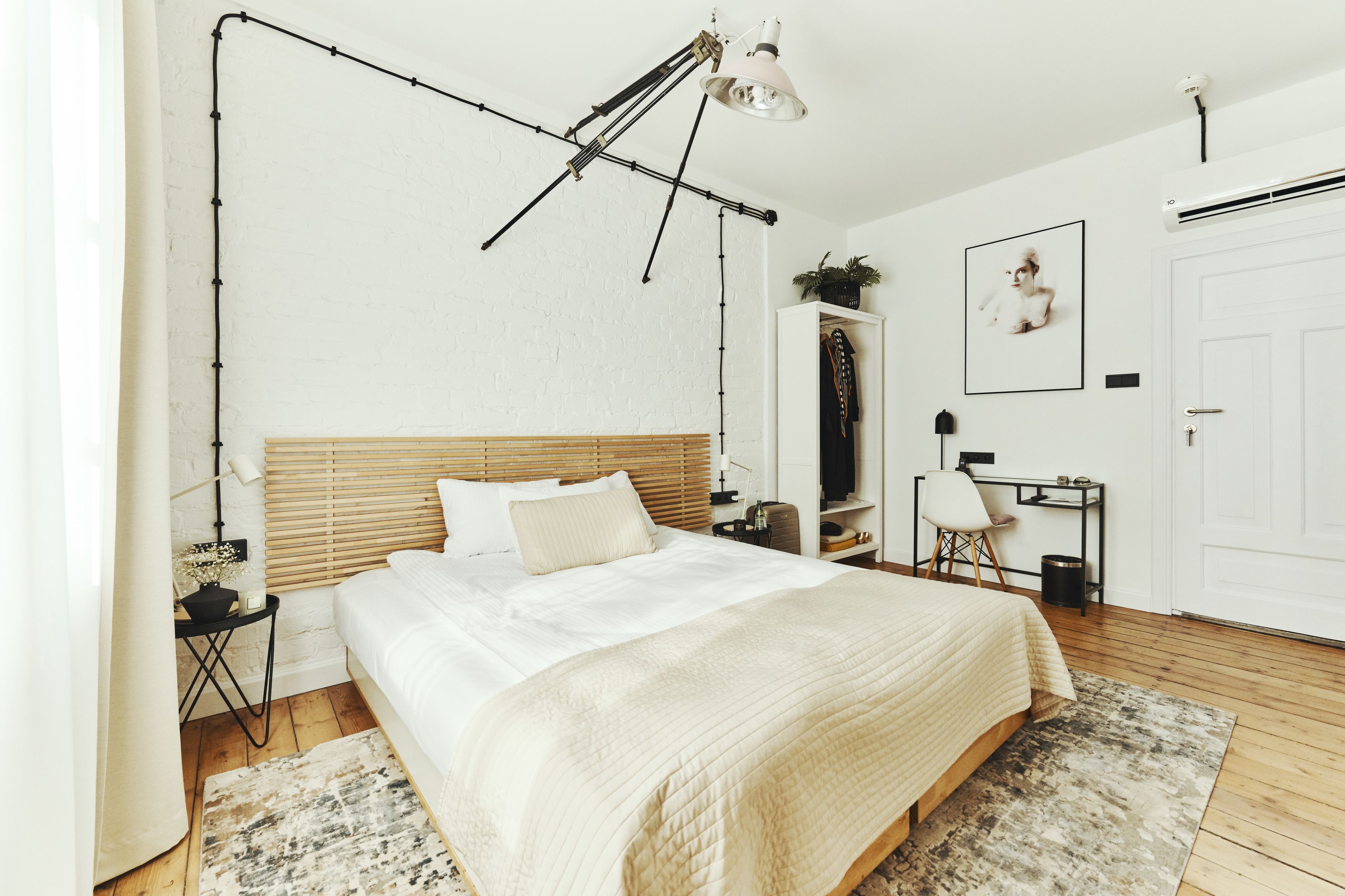 A bedroom with a large bed, a desk, a chair, a lamp, and a hanging light fixture.