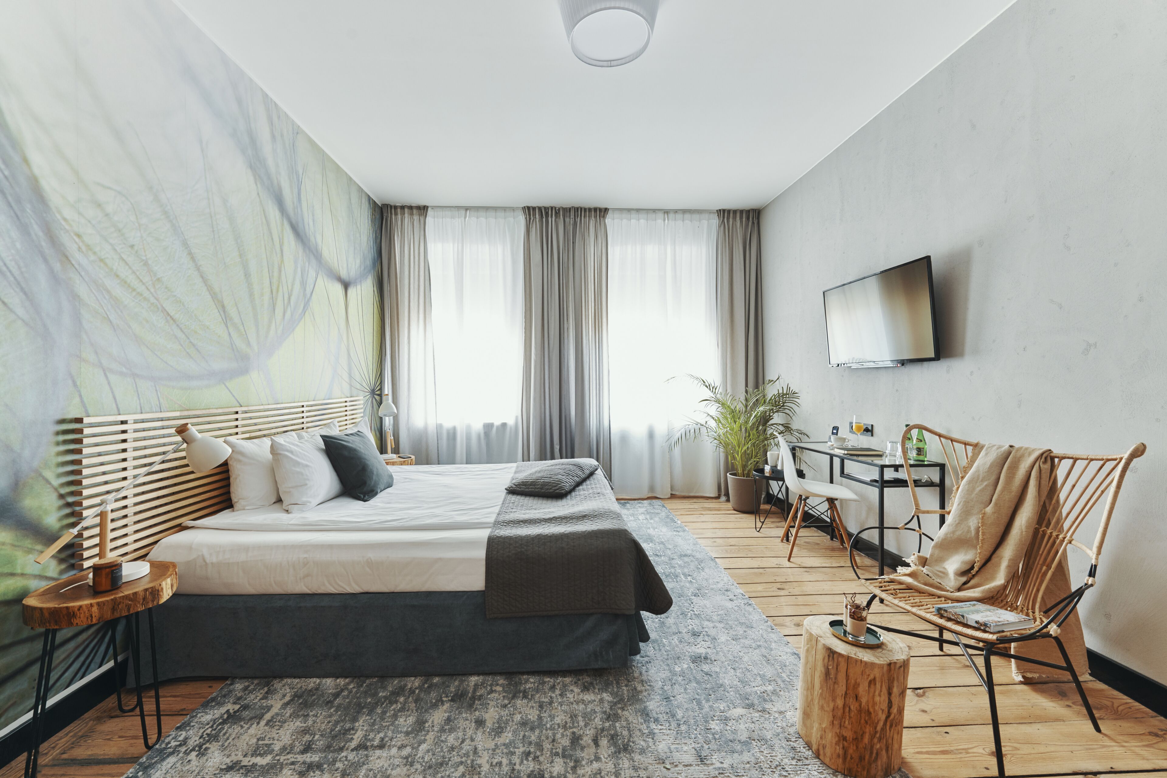Un dormitorio moderno con una cama grande, un escritorio, una silla y un televisor en la pared.