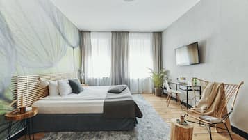 Un dormitorio moderno con una cama grande, un escritorio, una silla y un televisor en la pared.