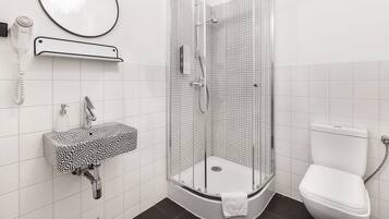 A modern bathroom with a shower, toilet, sink, and a hairdryer.