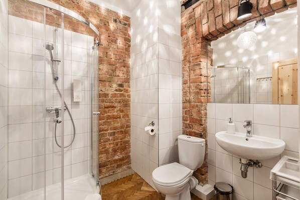 Un baño con ducha de vidrio, inodoro blanco y lavamanos.