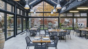 A restaurant with a modern interior, featuring black metal chairs and tables, large windows, and a brick wall visible through the glass. - Arthotel Stalowa 52 (Warsaw)