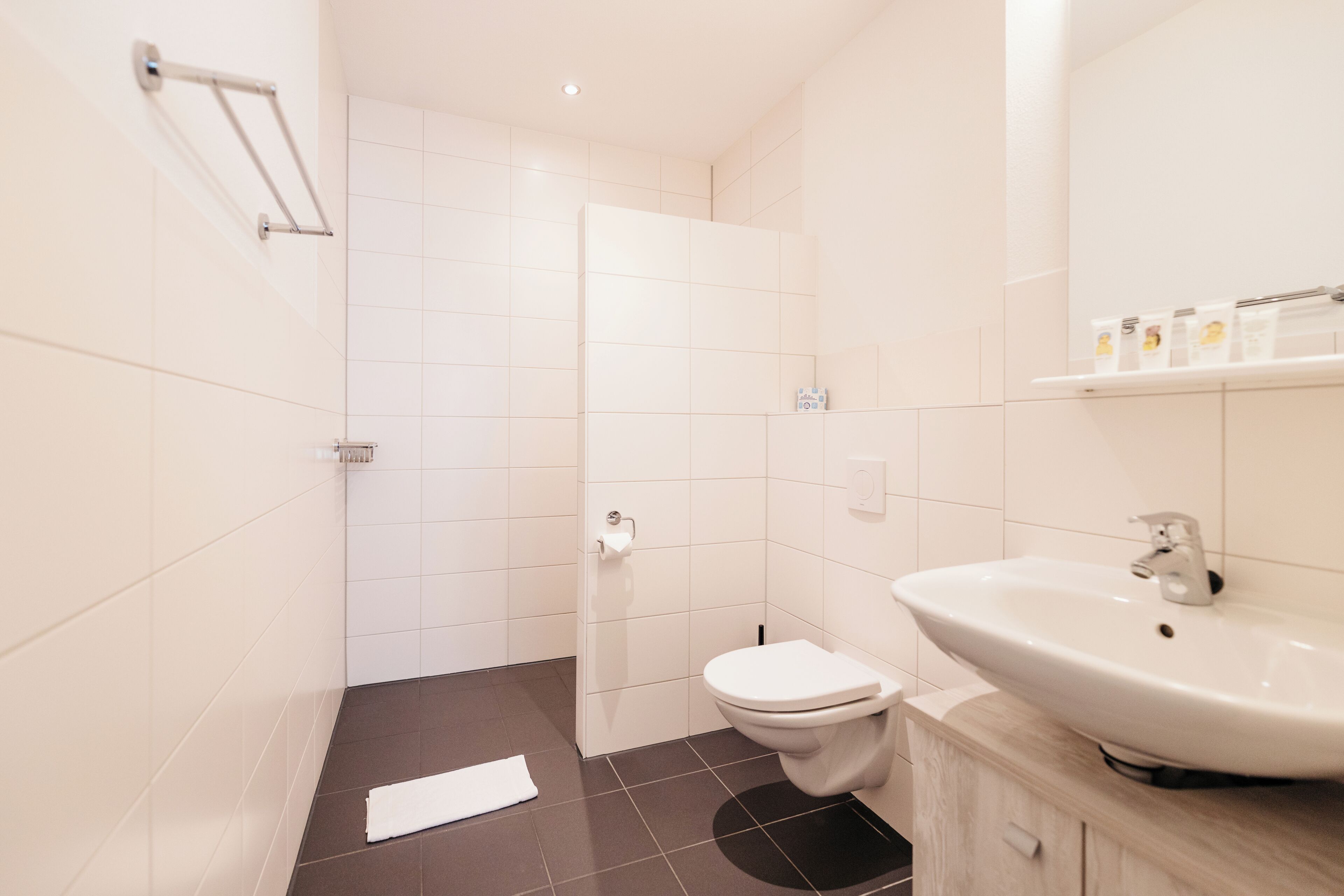 Un baño moderno con inodoro blanco, lavamanos y zona de ducha.