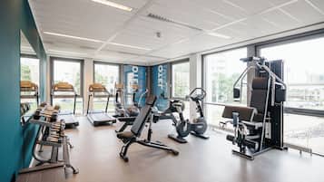 A gym with cardio machines, weight benches, and free weights.