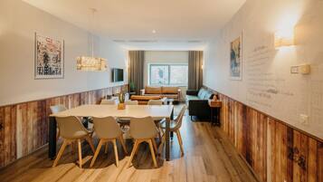 Un comedor moderno con una mesa y sillas de madera, un sofá y un ventanal con cortinas.