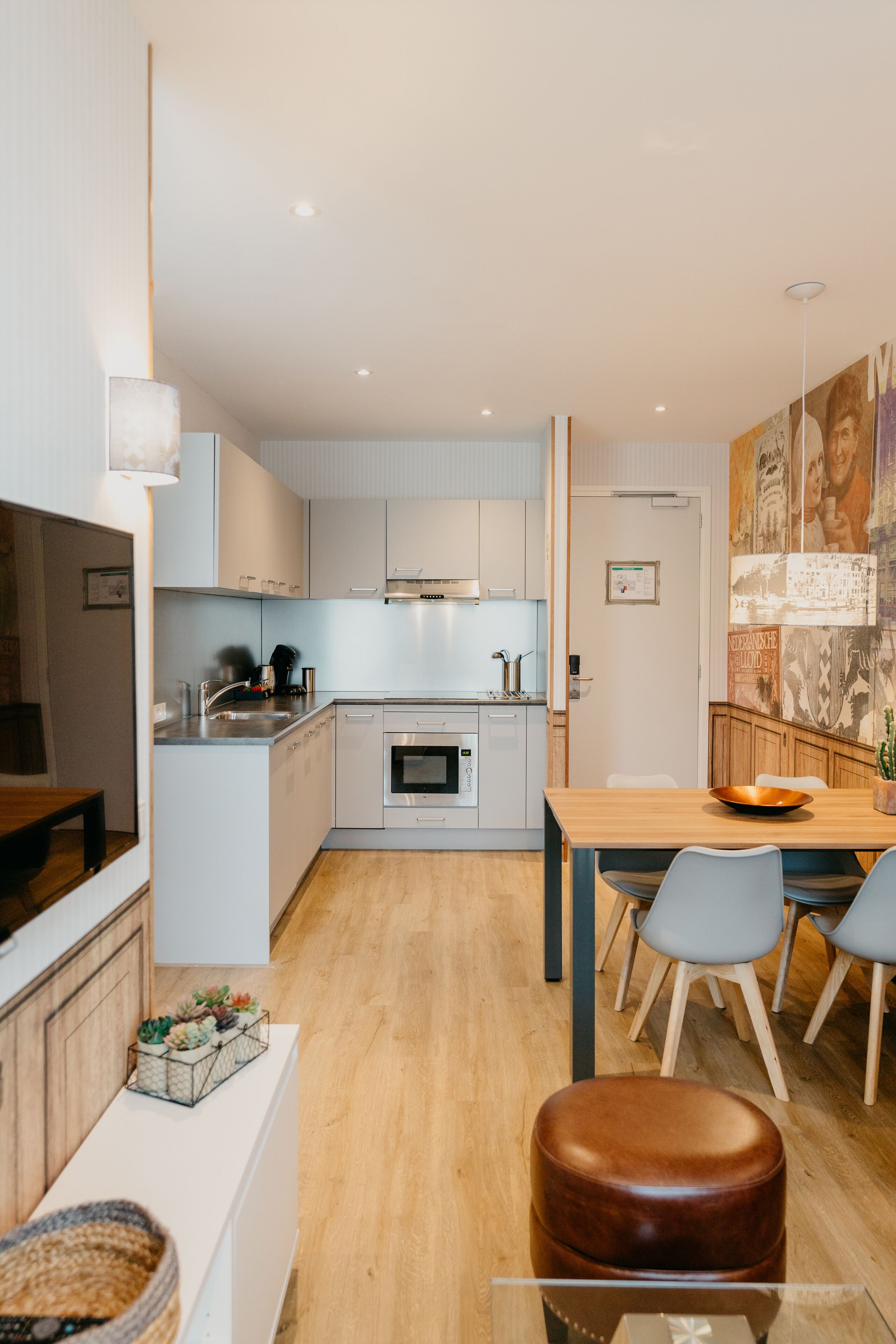 Een moderne keuken met witte kasten, een houten eettafel en een bruine leren kruk.