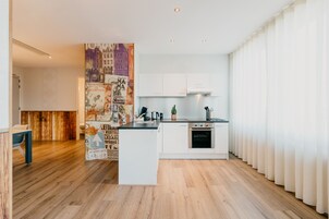 Cocina moderna con gabinetes blancos, una isla central y piso de madera.