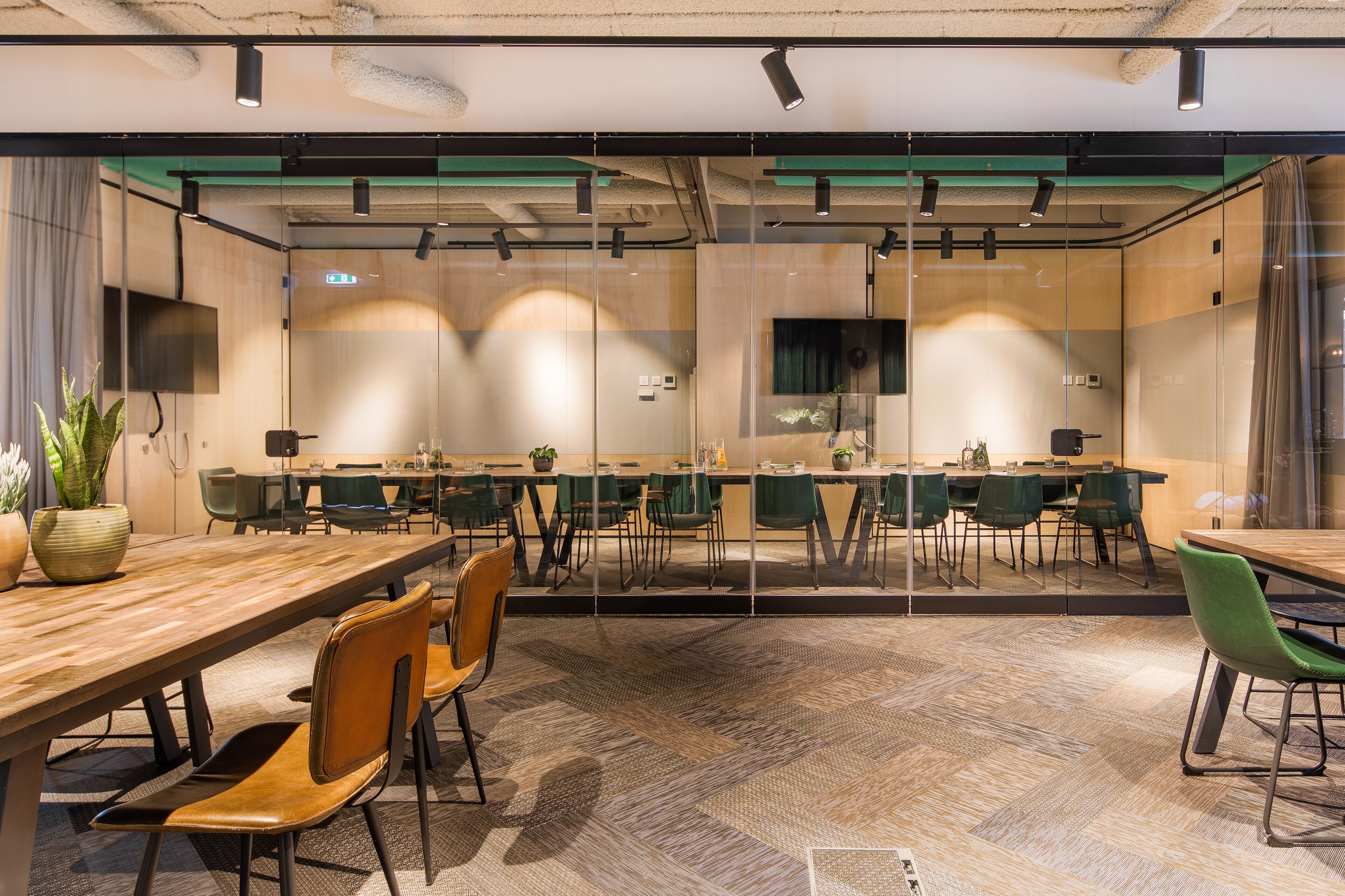 A modern conference room with glass walls, multiple tables, and chairs.