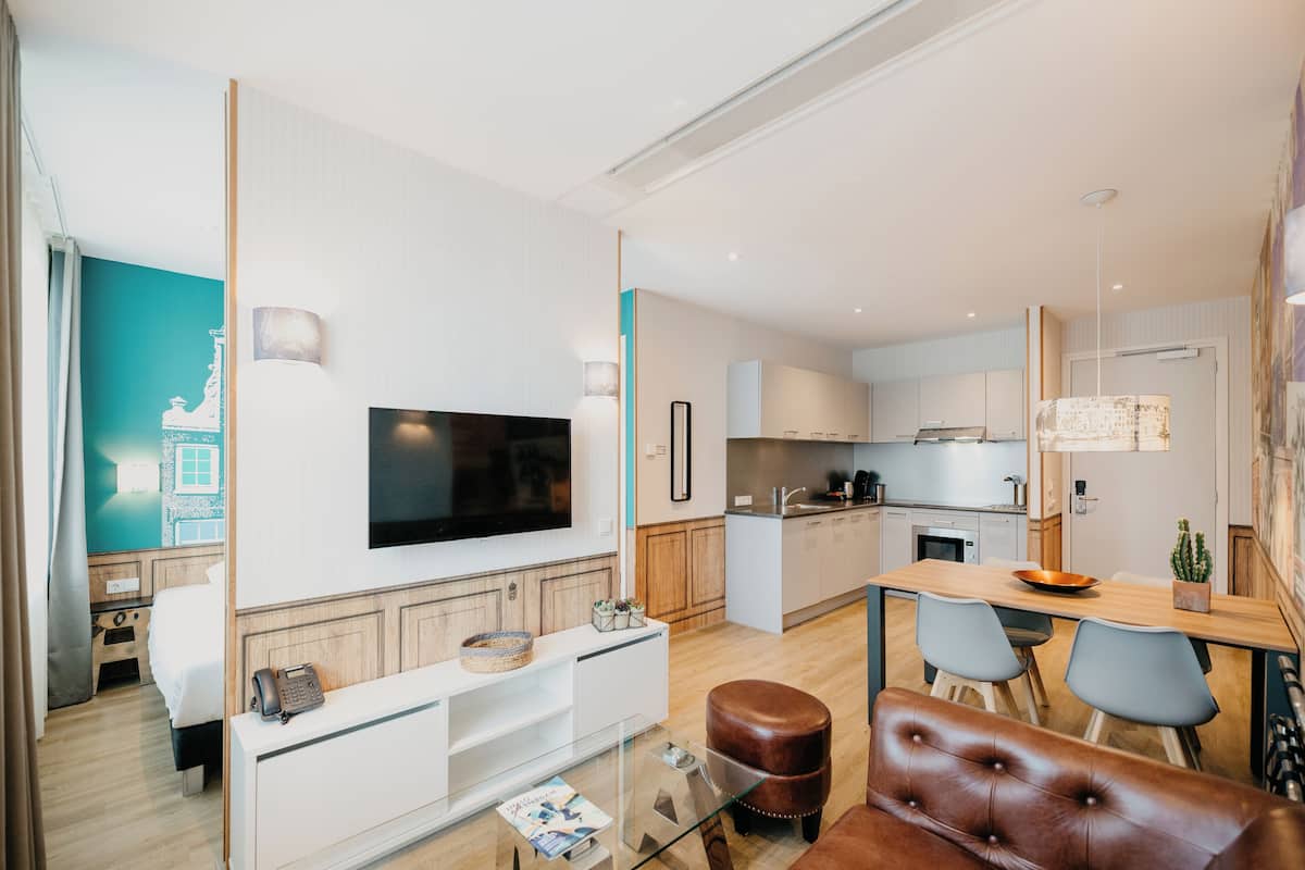 Une chambre d’hôtel moderne équipée d  ’une télévision, d’un coin repas et d’une cuisine.