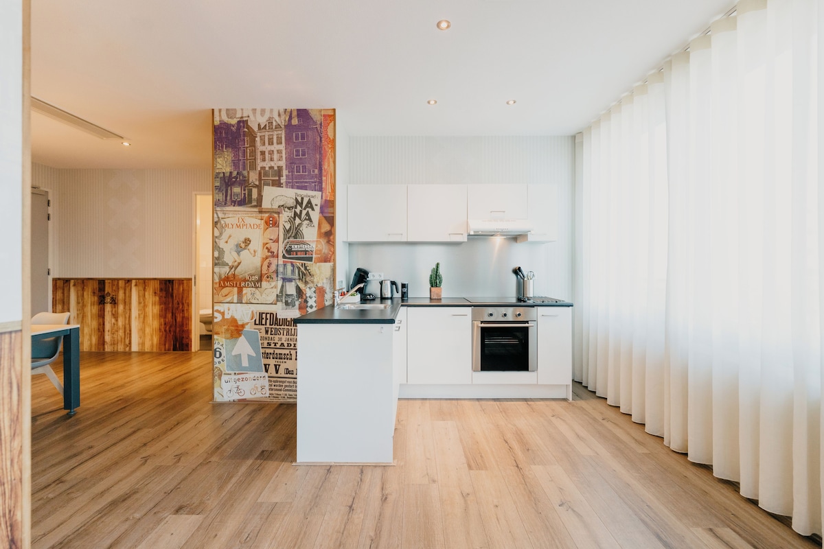 Een moderne keuken met witte kasten, een centraal eiland en een houten vloer.