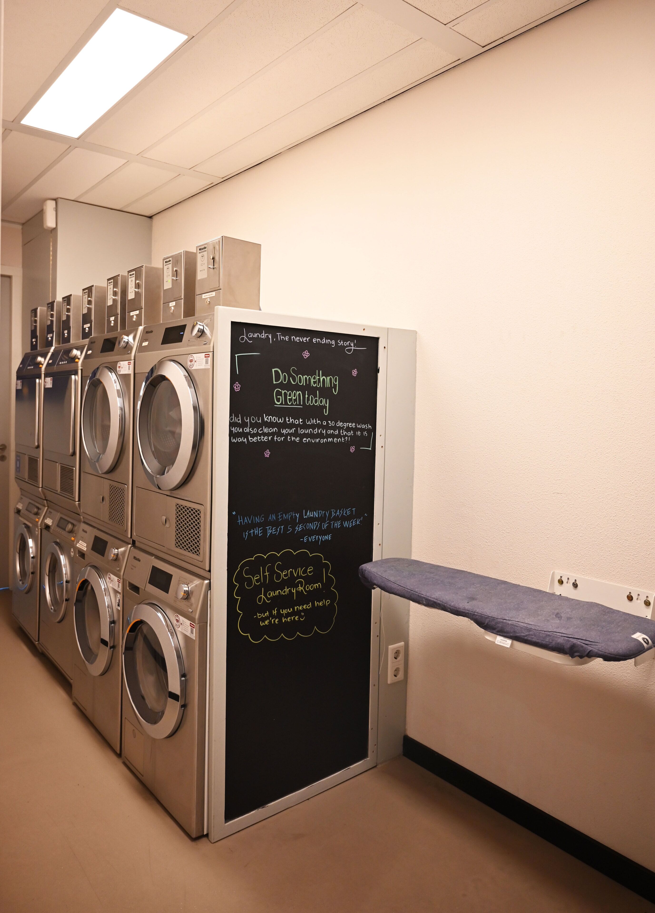 A laundry room with multiple washing machines and a chalkboard with motivational laundry tips.