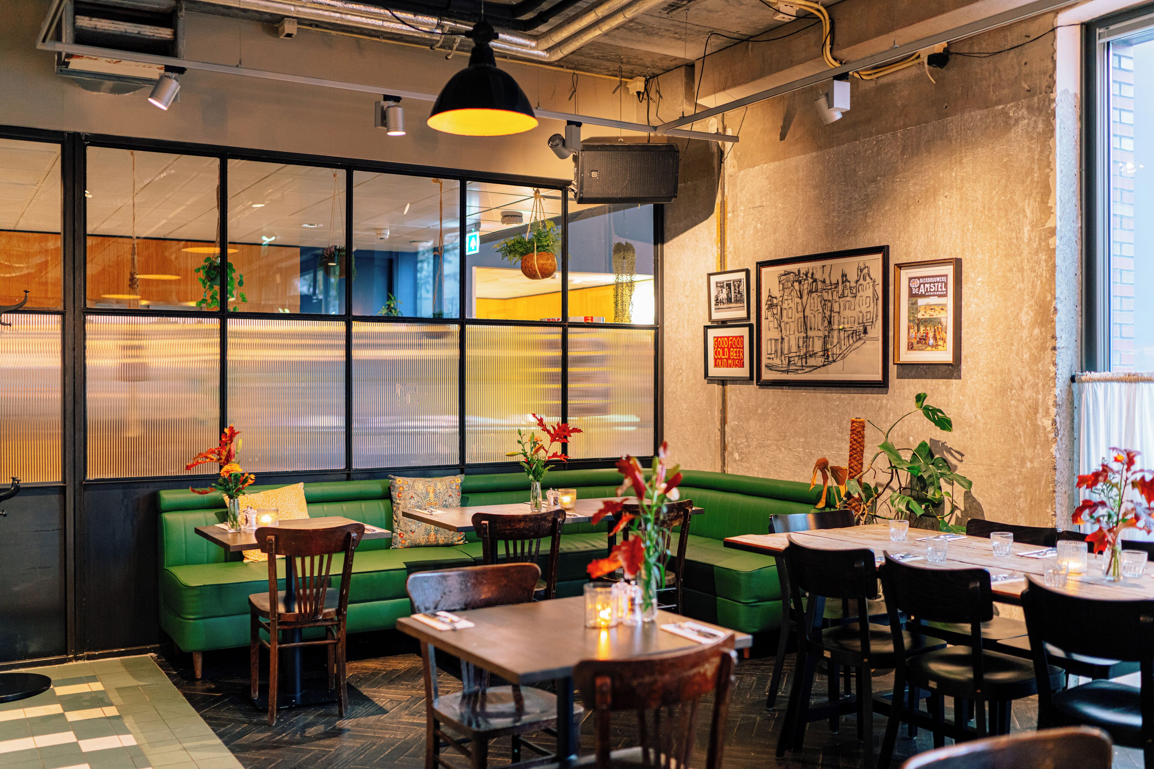 Un restaurante moderno con un sofá verde, mesas y sillas de madera.